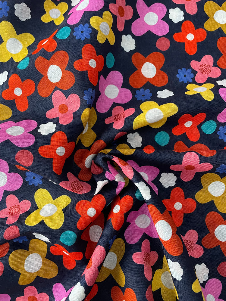 Colorful flower pattern on a dark blue background. Close up of the occasional slub in the fabric.