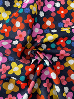 Colorful flower pattern on a dark blue background. Close up of the occasional slub in the fabric.