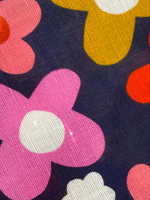 Colorful flower pattern on a dark blue background. Close up of the occasional slub in the fabric.